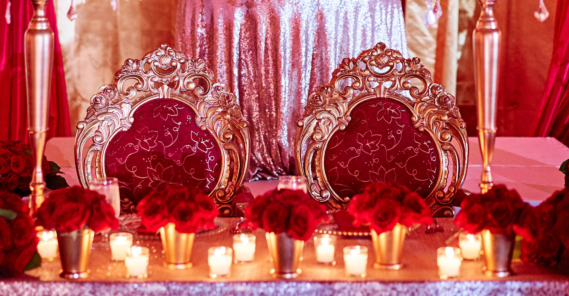 beautiful red chairs  with gold frame and table with candles and red roses at an indian wedding