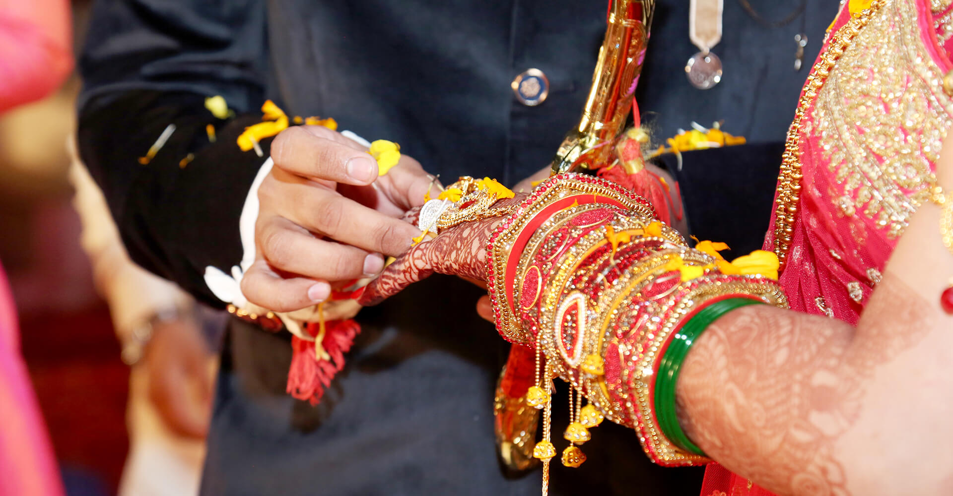 close-up of hands of indian groom placing wedding ring on his bride at an indian wedding