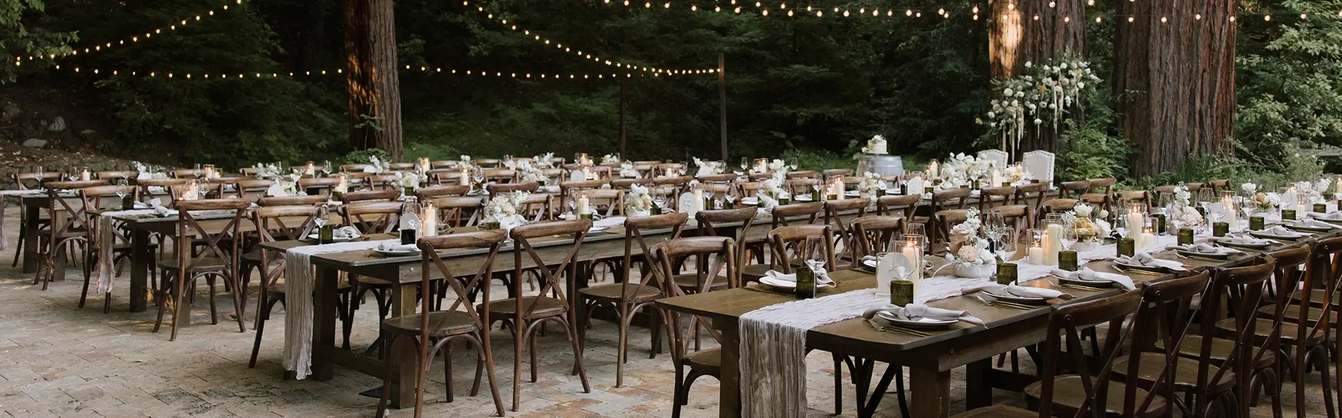 Outdoor Hindu wedding reception in California featuring long wooden tables, elegant seating, and ambient string lighting in a natural forest setting
